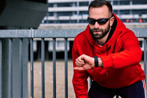 istock Attractive bearded runner in tracksuit resting and looking at smart watch his pulse. 1257526833