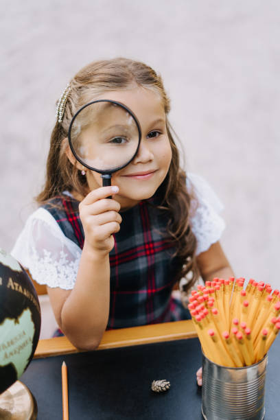 istock Pretty Primary Schoolgirl Look Through Magnifier 1257527382