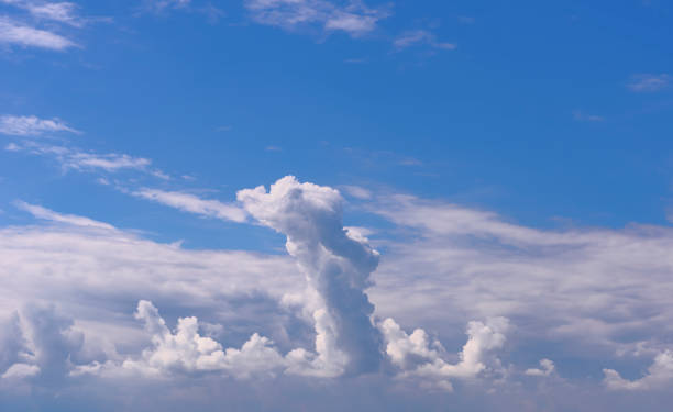 Dramatic skyscape - phallus shaped cloud piling up, huge cumulonimbus tower Out of an altocumulus clouds layer a phallus shaped cumulonimbus cloud tower rises high up into a deep blue sky.  A sky only, full-frame and close-up image of a cumulonimbus cloudscape with copy space. phallus shaped stock pictures, royalty-free photos & images