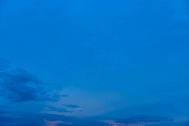 It’s the blue hour in October, the fall sky is really deep blue and a few clouds drift lazily across the skyscape. A sky only, full-frame and close-up image  with copy space.