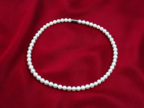 White pearl necklace on red silk texture satin velvet material