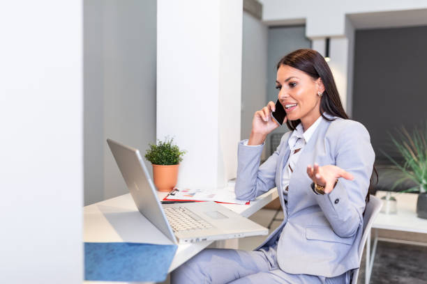 istock Business woman usingmobile phone, looking at laptop screen, chatting, reading or writing email, sitting in home office, female student doing homework, working on research project online 1257530789