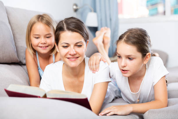 istock Woman reading book to daughters on sofa 1257531213