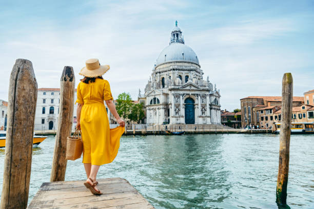 donna in abito estivo giallo a piedi da venezia guardando canal grande - canal sea journey romance foto e immagini stock