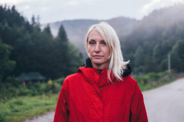 Outdoor Low angle image of a beautiful blonde woman who stands in fresh air against beautiful mountains.