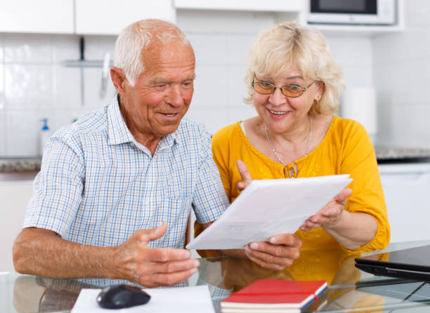 istock Happy mature couple with documents sitting at table in home 1257537813