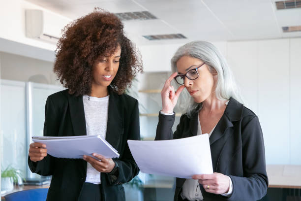 istock Content manager in glasses reading document with young colleague 1257538474