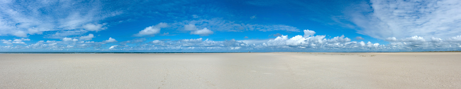 endless empty panoramic northsea beach background with wide sands an blue cloudy sky in the north of the island Fanø in Denmark