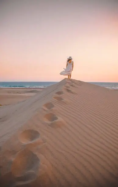 Photo of Sea and Desert - Young woman enjoying sunset on the sand hills of Patara, Antalya, Turkey