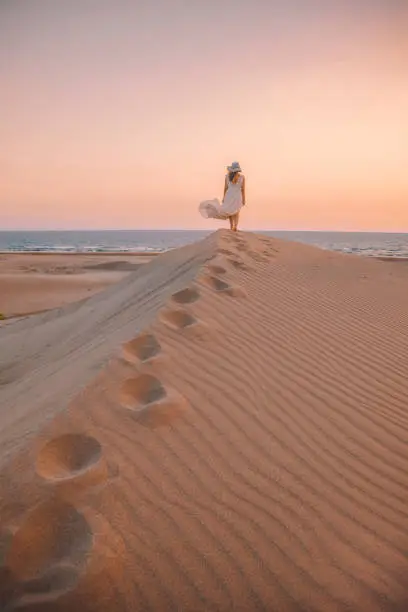 Photo of Sea and Desert - Young woman enjoying sunset on the sand hills of Patara, Antalya, Turkey