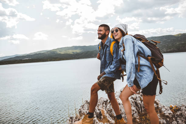 istock Hikers with backpacks on cliff enjoying at the mountain lake 1257543390