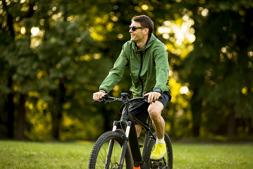 Handsome young man riding ebike in nature