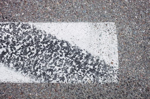 White asphalt mark with car tracks, white line on a street or road, texture as a background with space for text