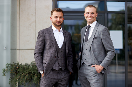 portrait of confident business partners outdoors, two caucasian men look at camera, wearing formal suit