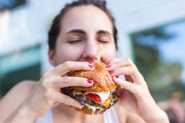 istock Woman eating cheeseburger 1257553479