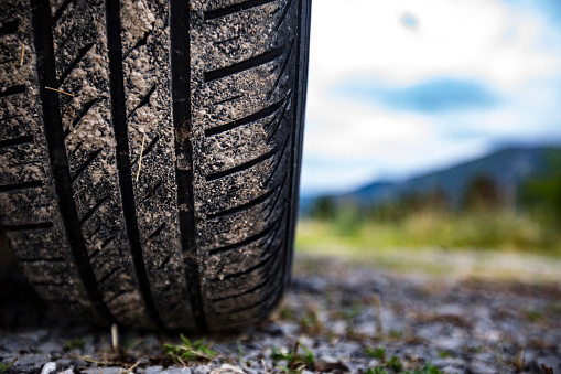 Dirty Car Tire in Rural Scene From Low Angle View.