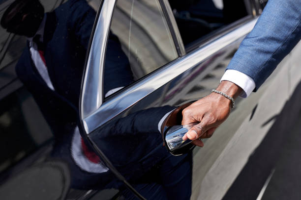 african taxi driver opening the door of car african taxi driver opening the door of car, help female client to get out of car. in luxurious executive car, business lady black taxi stock pictures, royalty-free photos & images