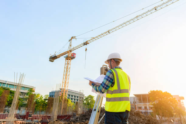 Surveying engineers are working together using theodolite on the construction site. The engineer is measuring the distance with a camera and directing the construction supervisor using radio communication. topography photos stock pictures, royalty-free photos & images