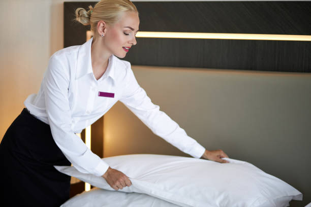 istock bautiful maid setting up white pillow on bed sheet in hotel room 1257559450