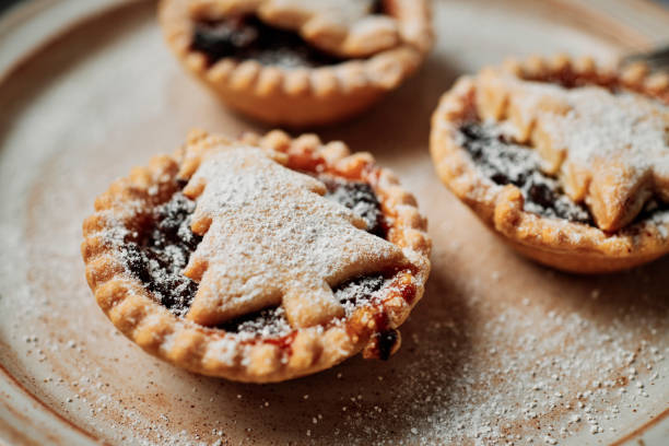 istock Three home made Mince Pies with Christmas Tree shaped tops, dusted with icing sugar on a rustic plate. 1257561057