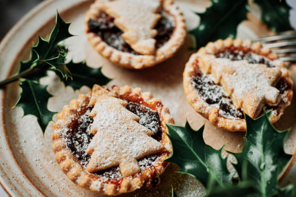 istock Three home made Mince Pies with Christmas Tree shaped tops, dusted with icing sugar on a rustic plate. 1257561063