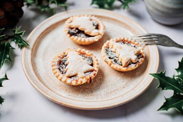 istock Three home made Mince Pies with Christmas Tree shaped tops, dusted with icing sugar on a rustic plate. 1257561158