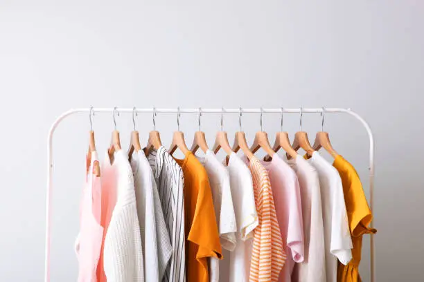 Photo of fashion clothes on a rack in a light background indoors. place for text