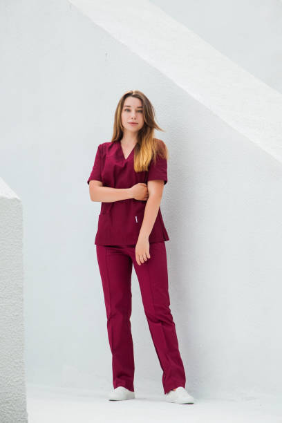 Medical students in burgundy red surgical suits standing in front of nursing school. Young girl transplantologist doctor. Medical students in burgundy red surgical suits standing in front of nursing school. Young transplantologist doctor. red medical scrubs stock pictures, royalty-free photos & images