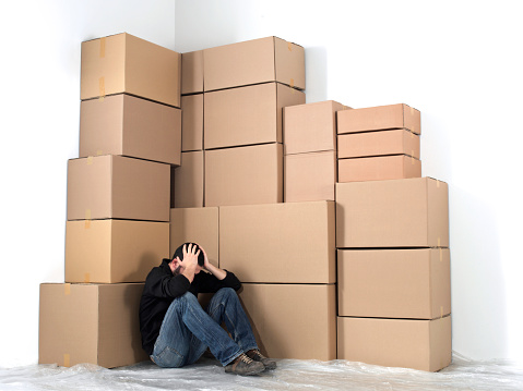 Woman sitting in front of a pile of  cardboard boxes