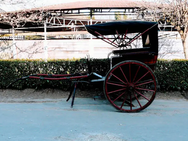An old AUTHENTIC horse cart with red black two wheels and wooden structure full length in France