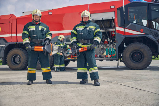 istock Strong handsome firefighters standing near the fire machine with equipment in hands 1257564434