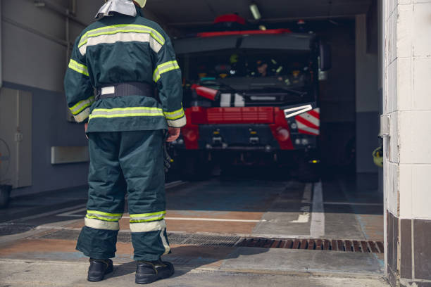 istock Tall man wearing protective green uniform standing at the fire station 1257564454