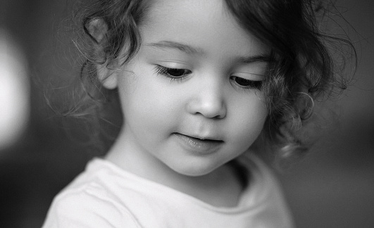 Monochrome portrait of sweet baby girl feeling innocent, looking down