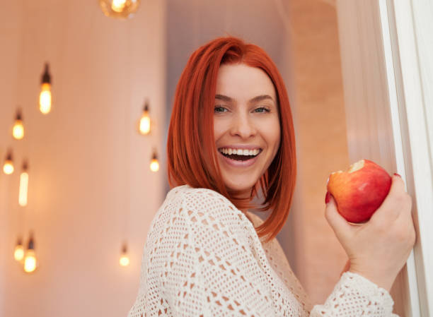 Beautiful redhead eating red apple