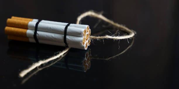 istock Cigarettes are twisted into a dynamite checker with a filament on a black reflective surface. 1257569493