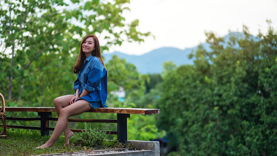 Portrait image of a beautiful young asian woman with mountains and green nature background