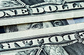 Eyes of Benjamin Franklin look through one dollars banknotes. Macro close up view.