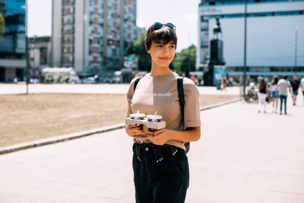 Young woman holding two cups of coffee to go Young woman holding two cups of coffee to go graphic t shirt stock pictures, royalty-free photos & images