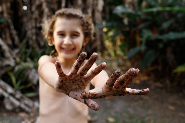 istock Smilling child playing in mud, showing muddy hands. 1257573599