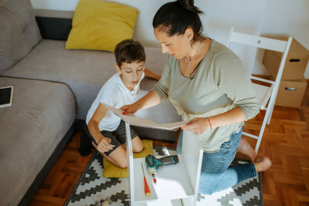 istock Boy and his mother are following assembling instruction and making bookshelf 1257575841