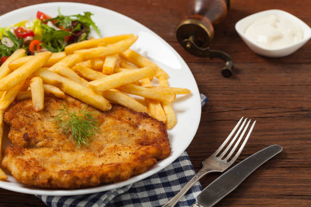 Chicken schnitzel, served with fries and salad. Chicken schnitzel, served with fries and salad. Natural wooden background. Front view. schnitzel stock pictures, royalty-free photos & images