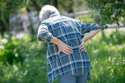 Gardening drawbacks. A senior woman having a back pain outdoor