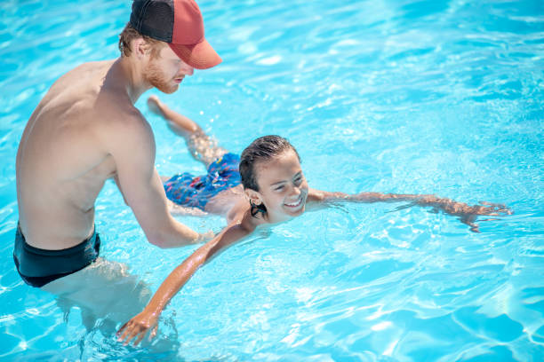 istock Man supporting boy on water in the pool 1257581934