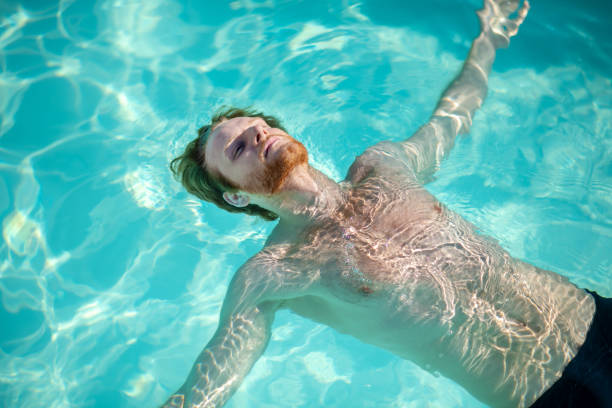 istock Young bearded man lying in water on his back 1257582031