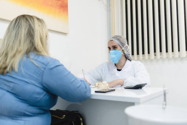 covid19: medico donna che frequenta una paziente in ufficio - dentist dentist office patient discussion foto e immagini stock
