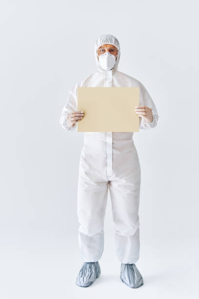 istock Doctor in protective medical suit showing blank placard with copy space for text 1257583465