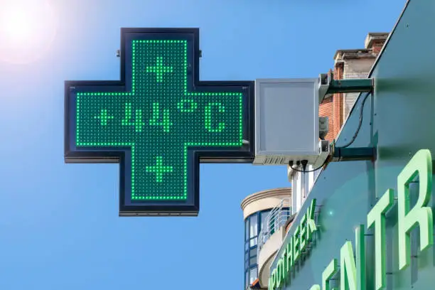 Thermometer in green pharmacy screen sign displays extremely hot temperature of 44 degrees Celsius during heatwave / heat wave in summer in Belgium