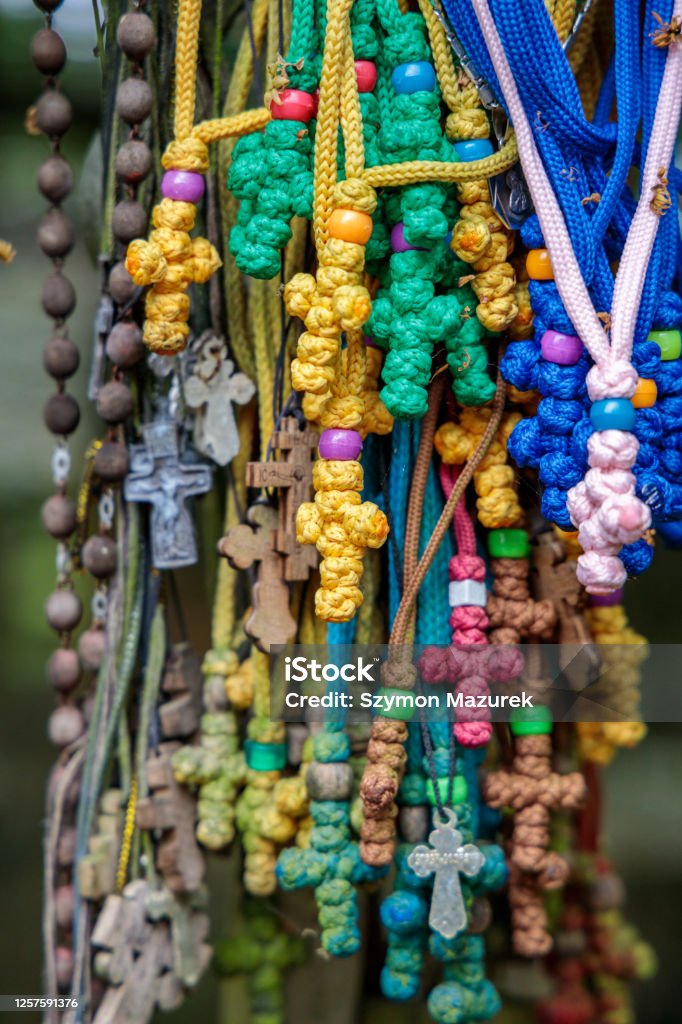 colorful crosses made of thread on the Holy Mountain of Grabarka in Poland The crosses litter the Holy Mountain of Grabarka in Poland, coming in all shapes and sizes: metal, wooden, ornamental and plain. Some tower over a dozen feet in the air while others are small, some hang on a string dangling from the arms of others. Rosary beads, photos, amulets, and letters are stapled, tied, or left to sit on the crosses, all in various states of atrophy. Most crosses read in Cyrillic text “Lord, have mercy (Spasi Hospodi)” or list the names and ailments of those in need of healing or salvation. Rosary Beads Stock Photo
