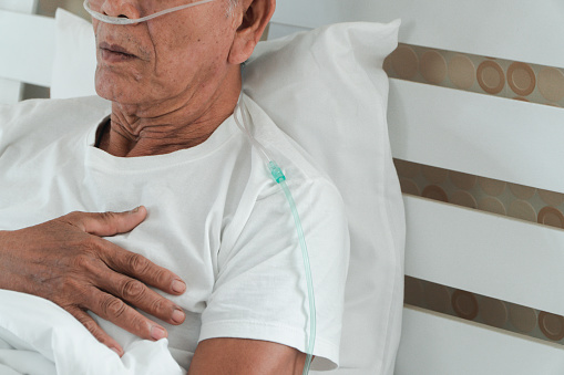 Triste hombre de la tercera edad acostado en la cama del hospital y con un tubo respiratorio nasal para el tratamiento respiratorio. Concepto de atención sanitaria para ancianos, coronavirus de cuarentena (COVID-19) photo