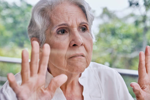 istock Lockdown despair Hispanic senior woman looking through window 1257591652